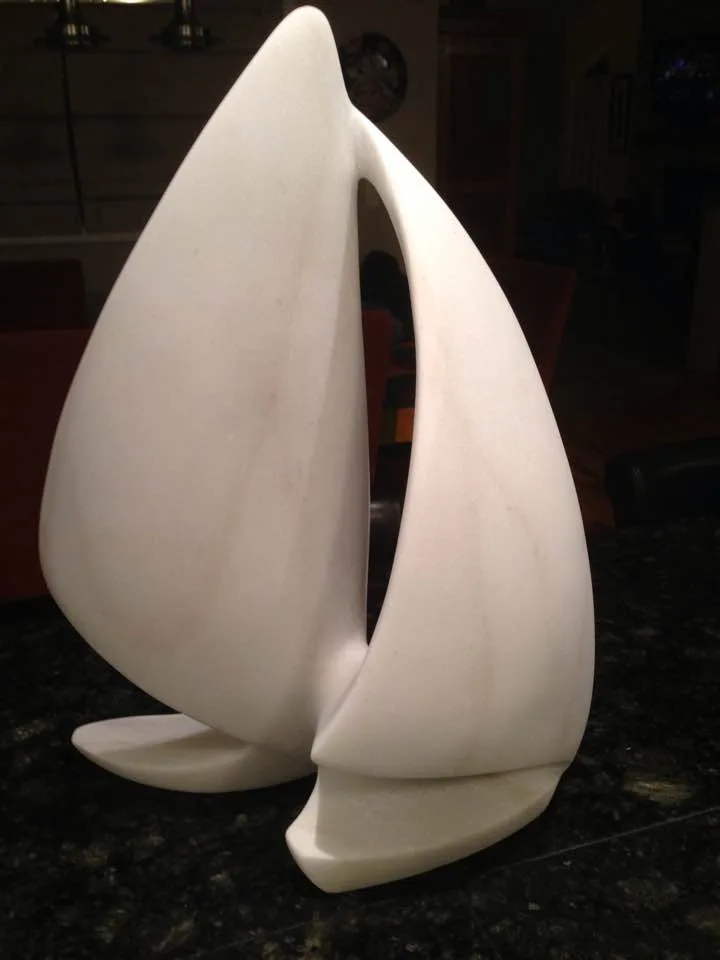 Abstract stone sculpture with smooth curved organic forms and a central void.