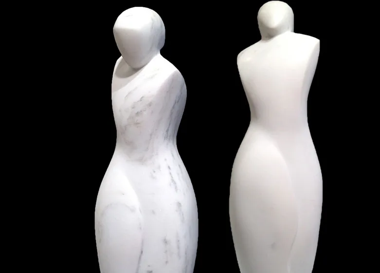 Two carved stone female figures shown front and back, minimally abstracted with headless forms.