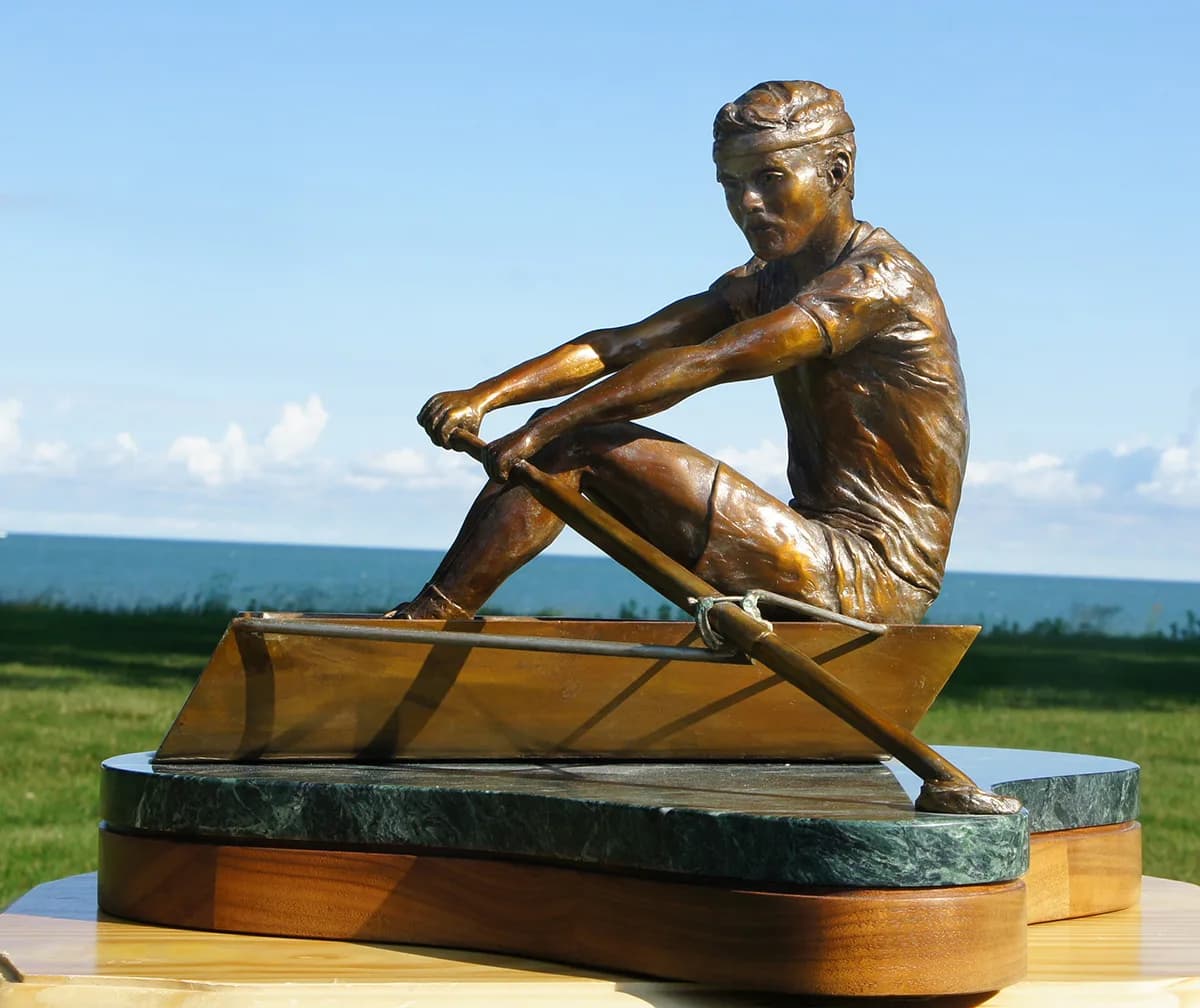Bronze sculpture of a rower seated in a boat, with the Boulder Flatirons visible in the background landscape.