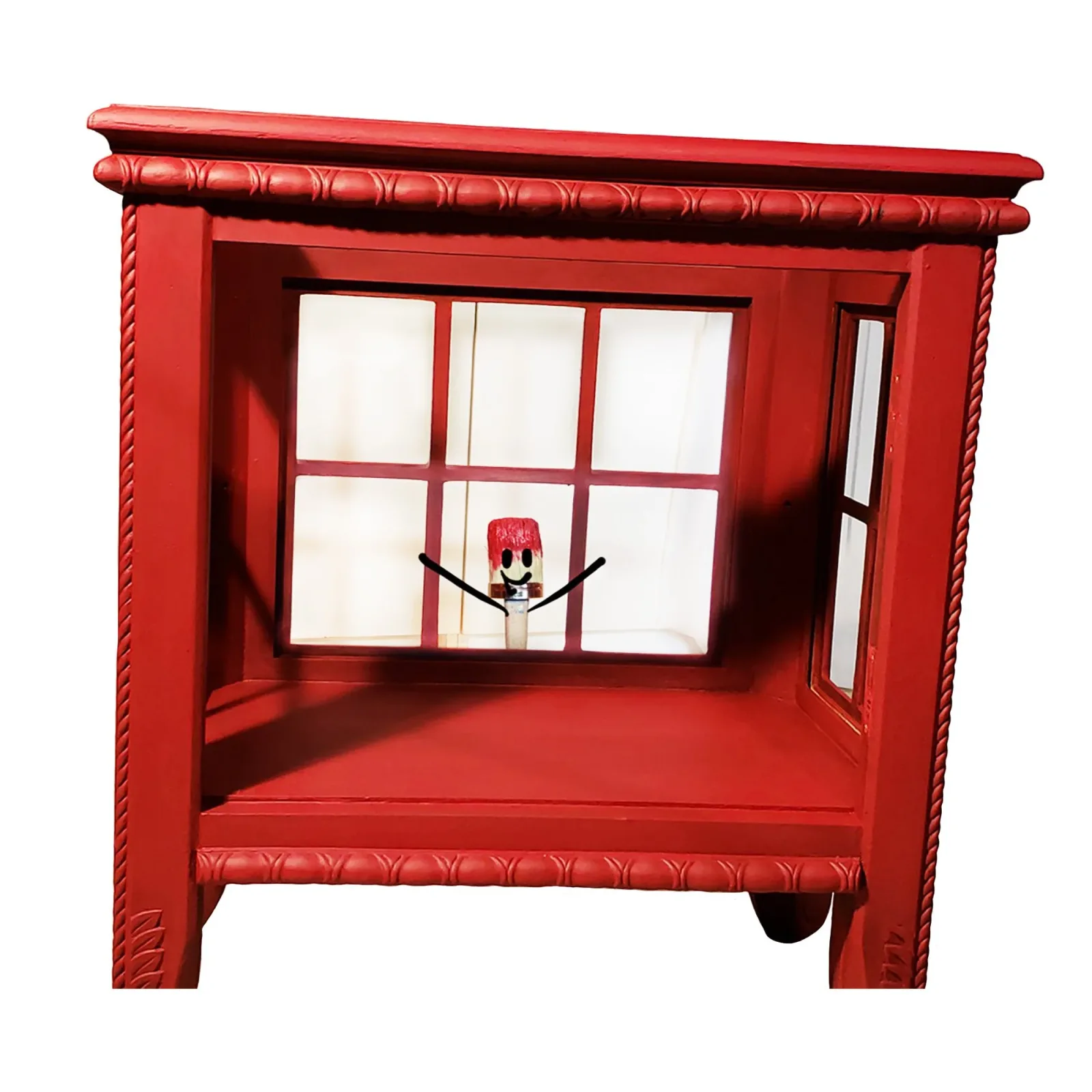 A bright red wooden shelter or booth with a whimsical clock figure visible through its gridded window.