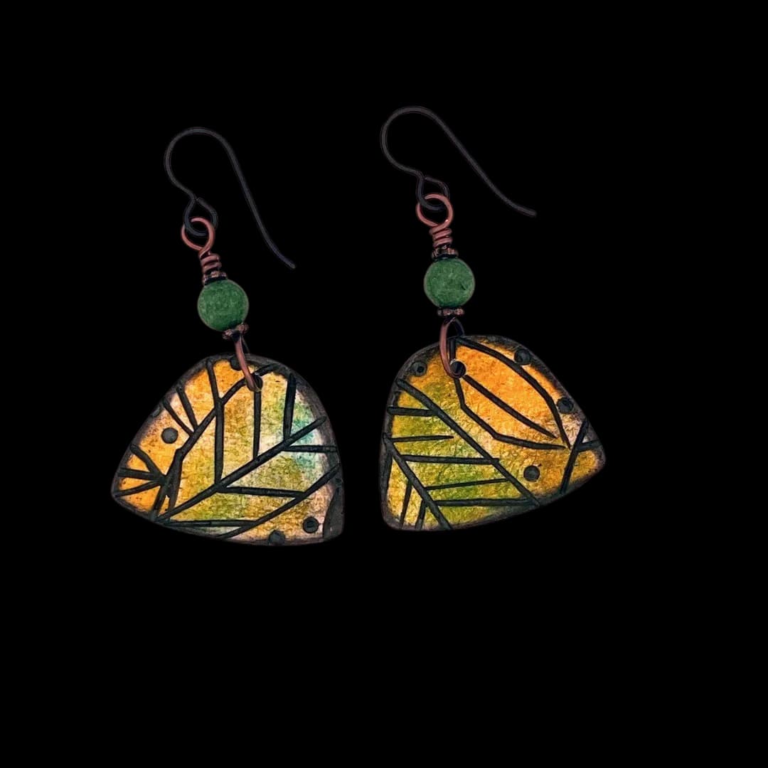 Pair of enameled copper leaf earrings with green stone accents and hand-forged metalwork details.