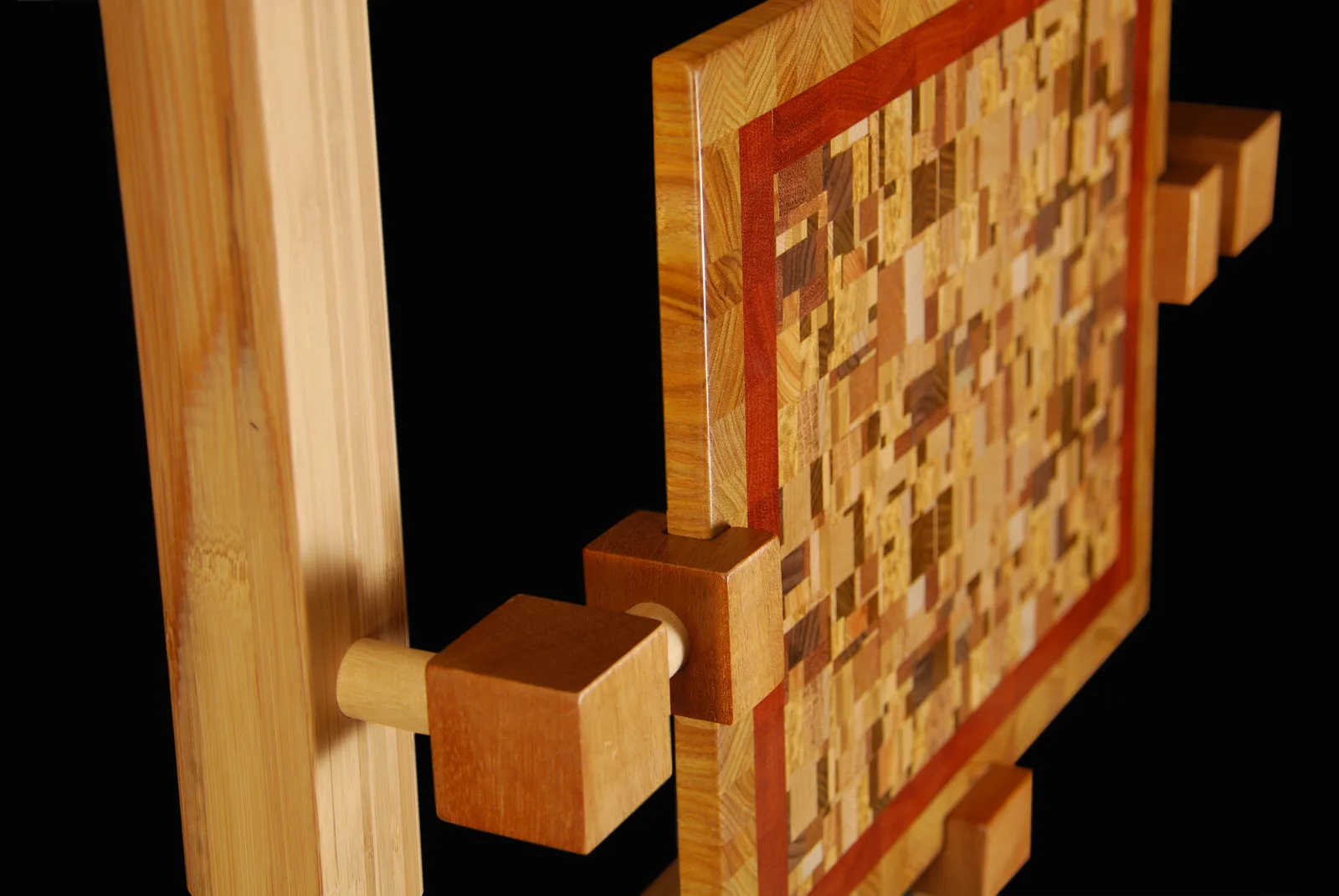 Abstract wooden sculpture constructed from stacked and interlocking blocks of varied grain and wood tones.