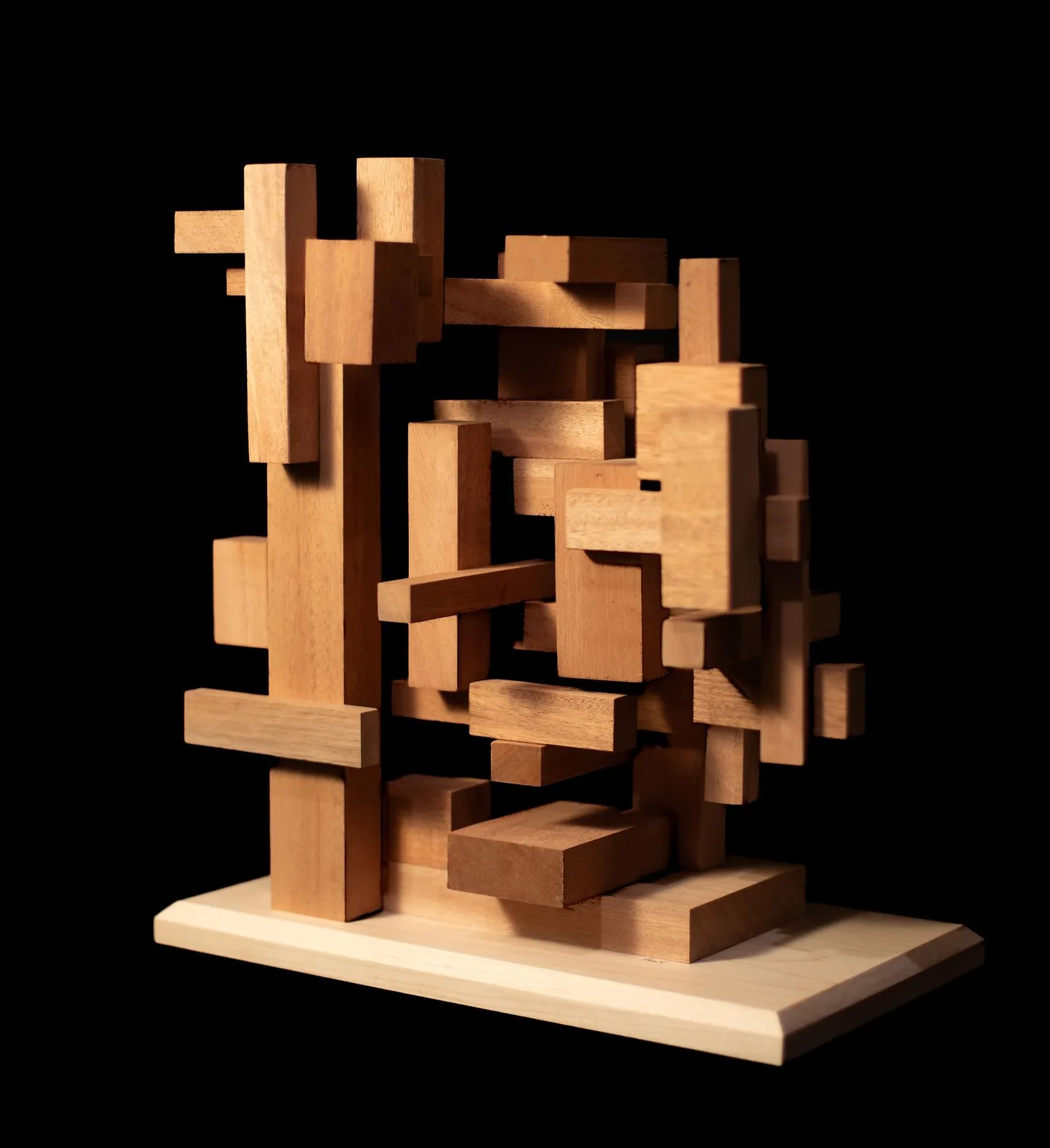 Abstract wooden sculpture composed of interlocking rectangular blocks and planes against a black background.