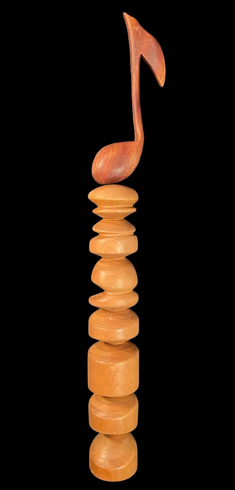 Stacked wooden forms crowned with a carved musical note in warm-toned wood.