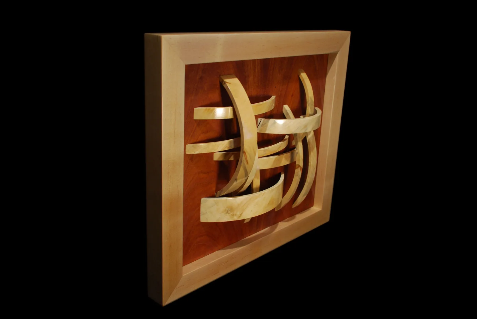 Abstract wooden relief sculpture in light and dark woods with curved carved forms.