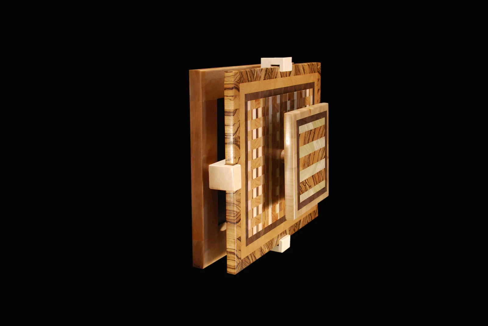 Dimensional wood sculpture with geometric inlay and contrasting wood tones, photographed against black.