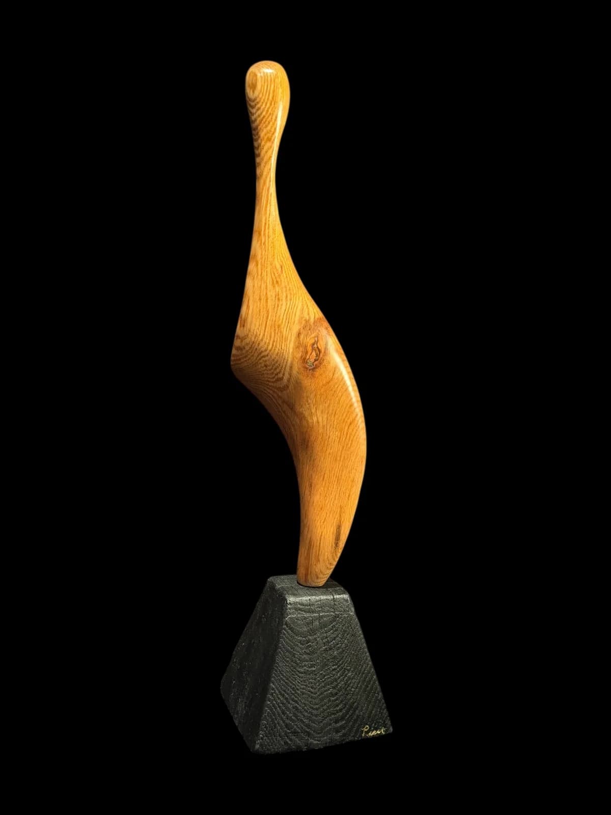 Abstract wooden sculpture with organic curved form on a dark stone base.