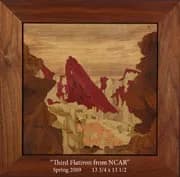 Wood inlay landscape depicting the Boulder Flatirons in warm earth tones within a wooden frame.