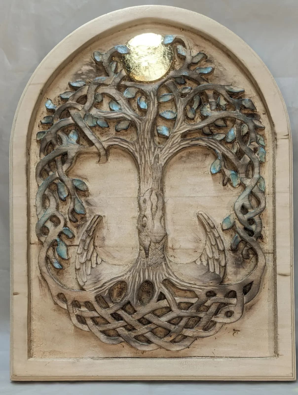 Stone relief carving of a tree with leafy canopy and interlaced root system, accented with turquoise inlay.