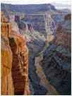 A photograph of a deep canyon with layered sandstone walls and a river winding through the gorge below.