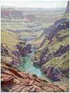Aerial landscape photograph of a rugged canyon with turquoise stream flowing through layered geology.