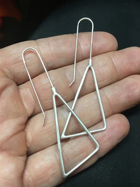 Pair of abstract geometric wire earrings in brushed metal with clean linear forms.