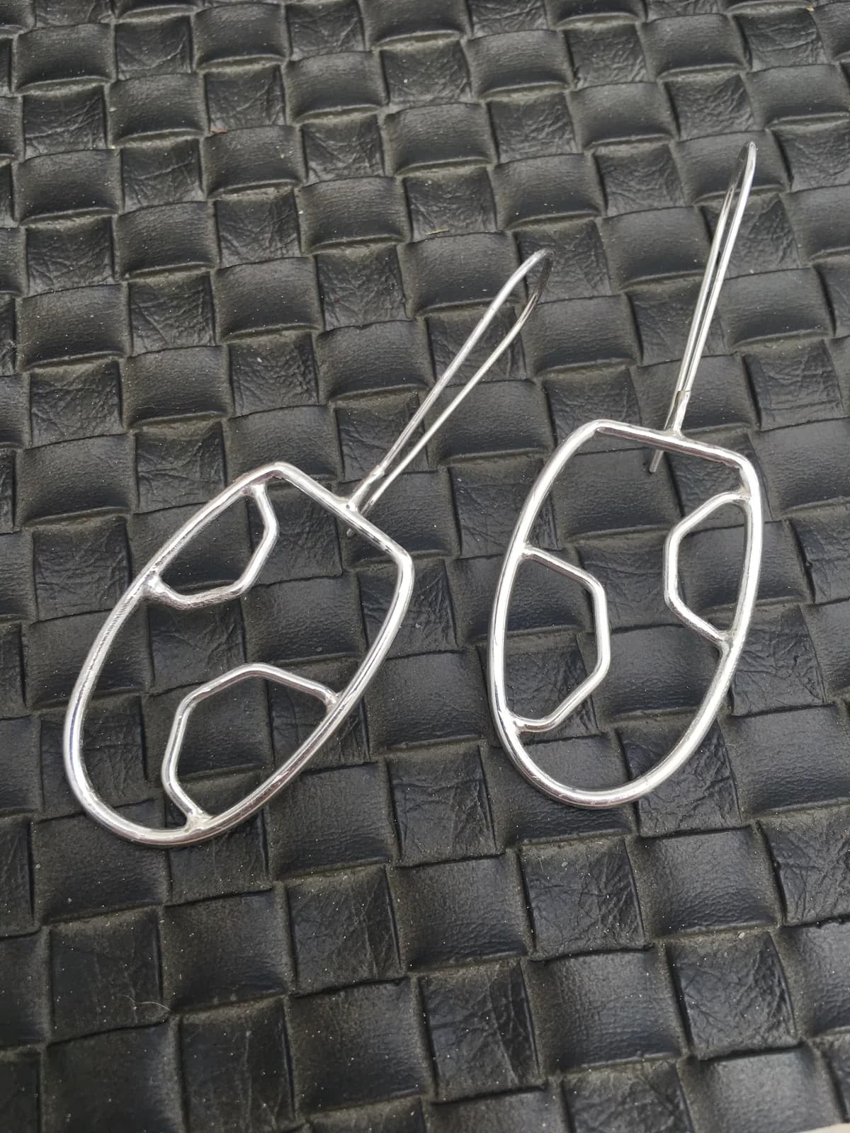 Pair of hand-formed wire earrings with organic sculptural shapes, crafted from polished metal.