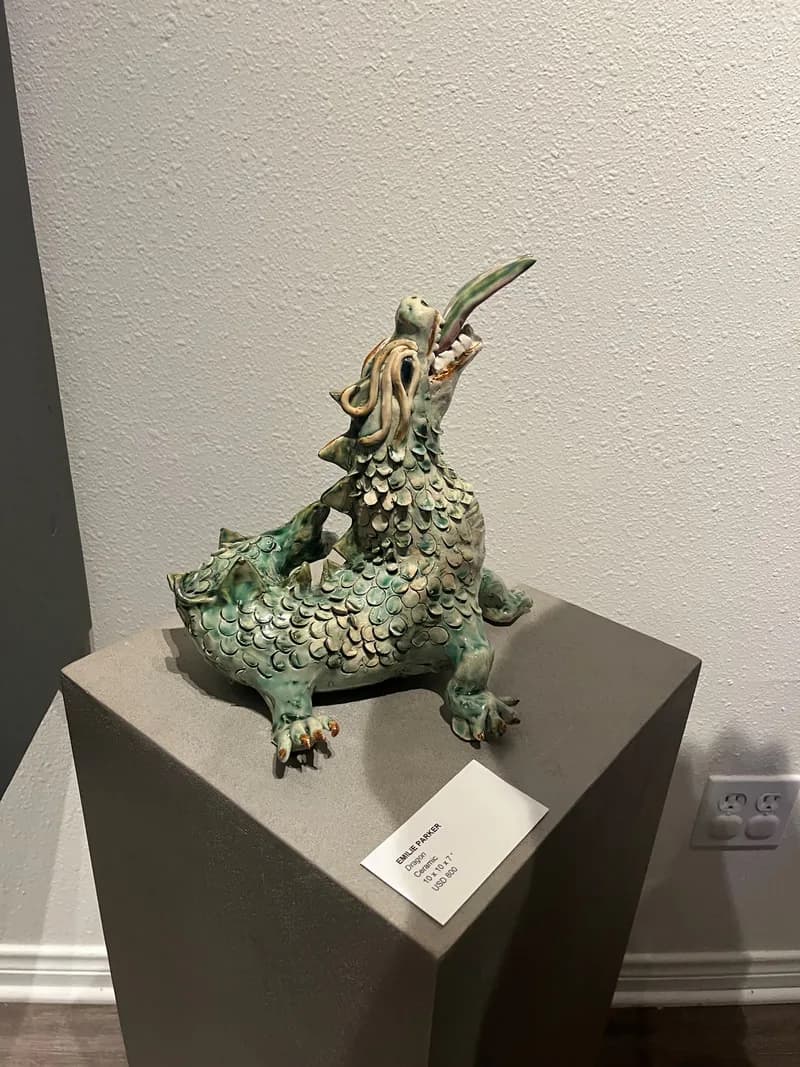 A bronze dragon sculpture with verdigris patina and ornamental details, mounted on a display pedestal.