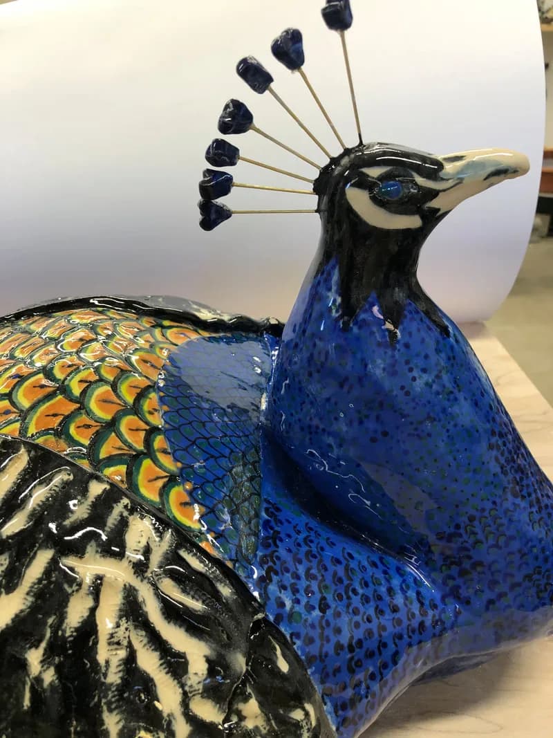 Hand-painted ceramic peacock sculpture with cobalt blue glaze, gold and black feather detailing.