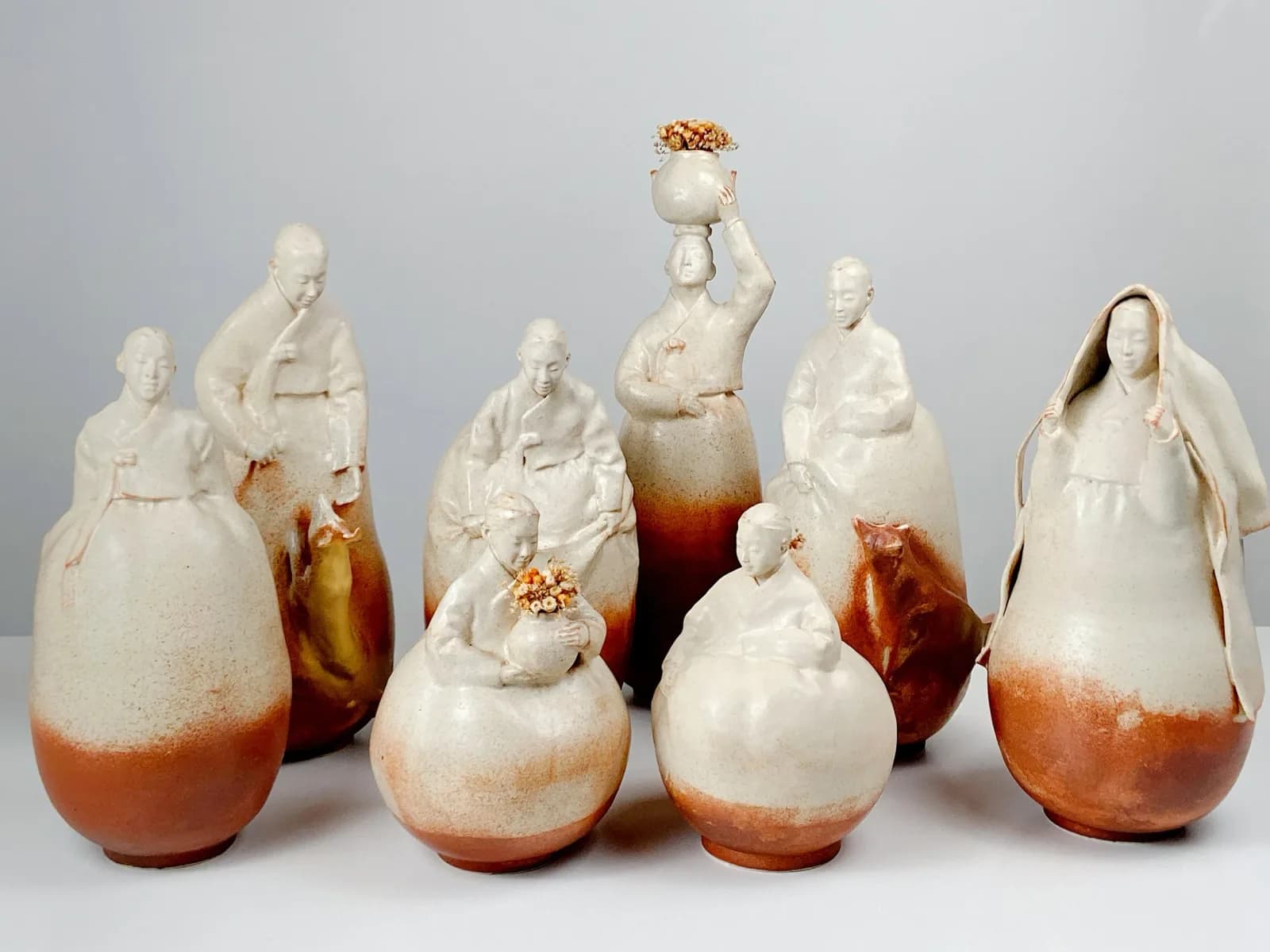 A series of ceramic vessels combining portrait heads and rounded clay forms with reactive glaze effects.