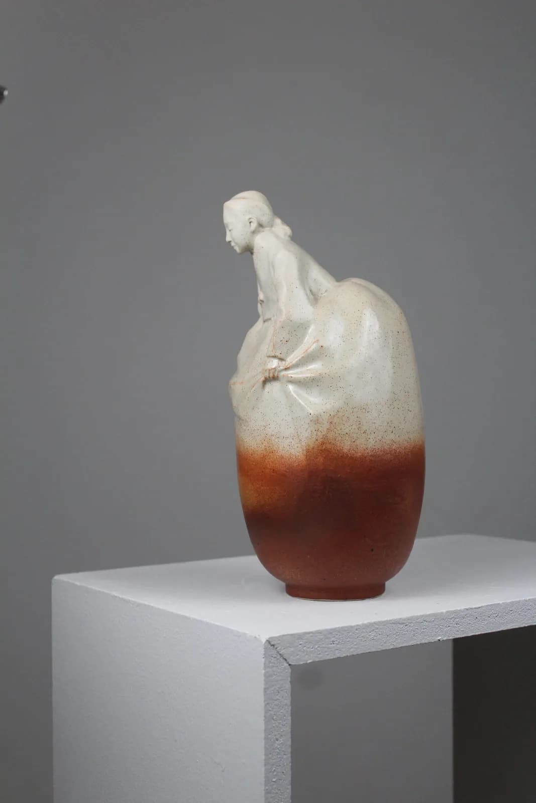 Ceramic vessel with organic figurative form in cream and rust-toned glaze.