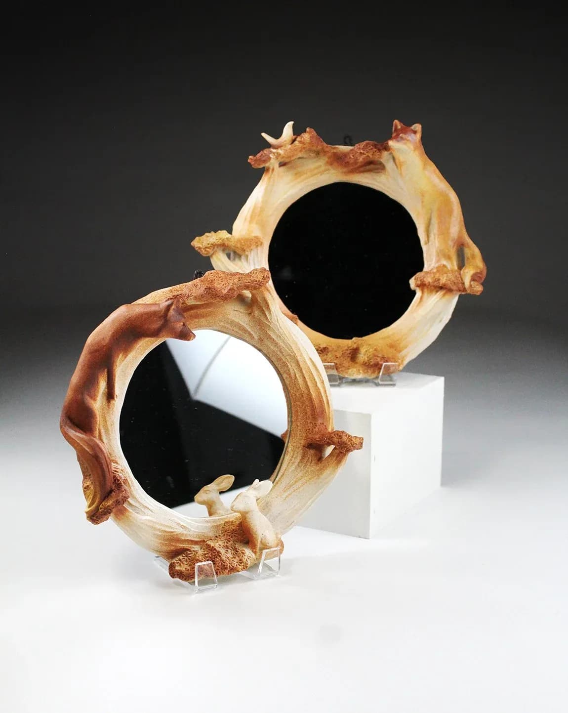 Two ceramic sculptural forms with abstracted animal limbs frame circular voids in glazed stoneware.