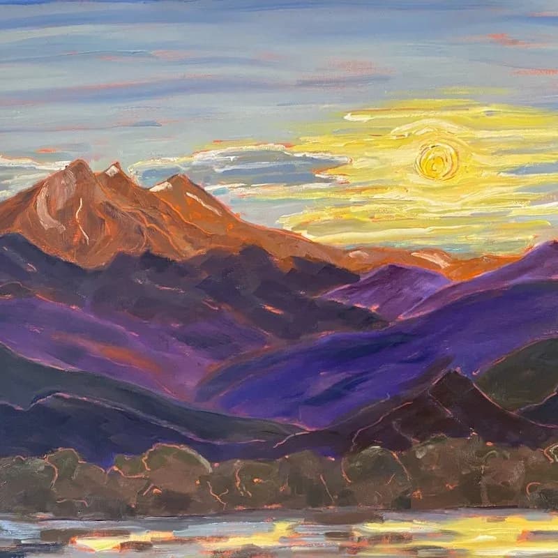 A mountain landscape with layered purple and rust peaks beneath a golden, swirling sky.