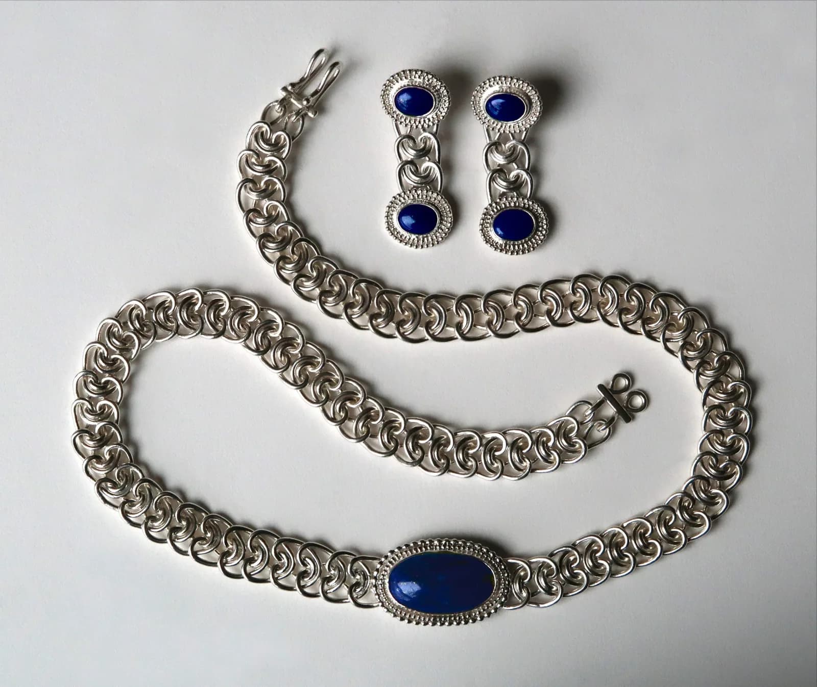 Silver and lapis lazuli jewelry set comprising a bracelet, necklace, and matching drop earrings.