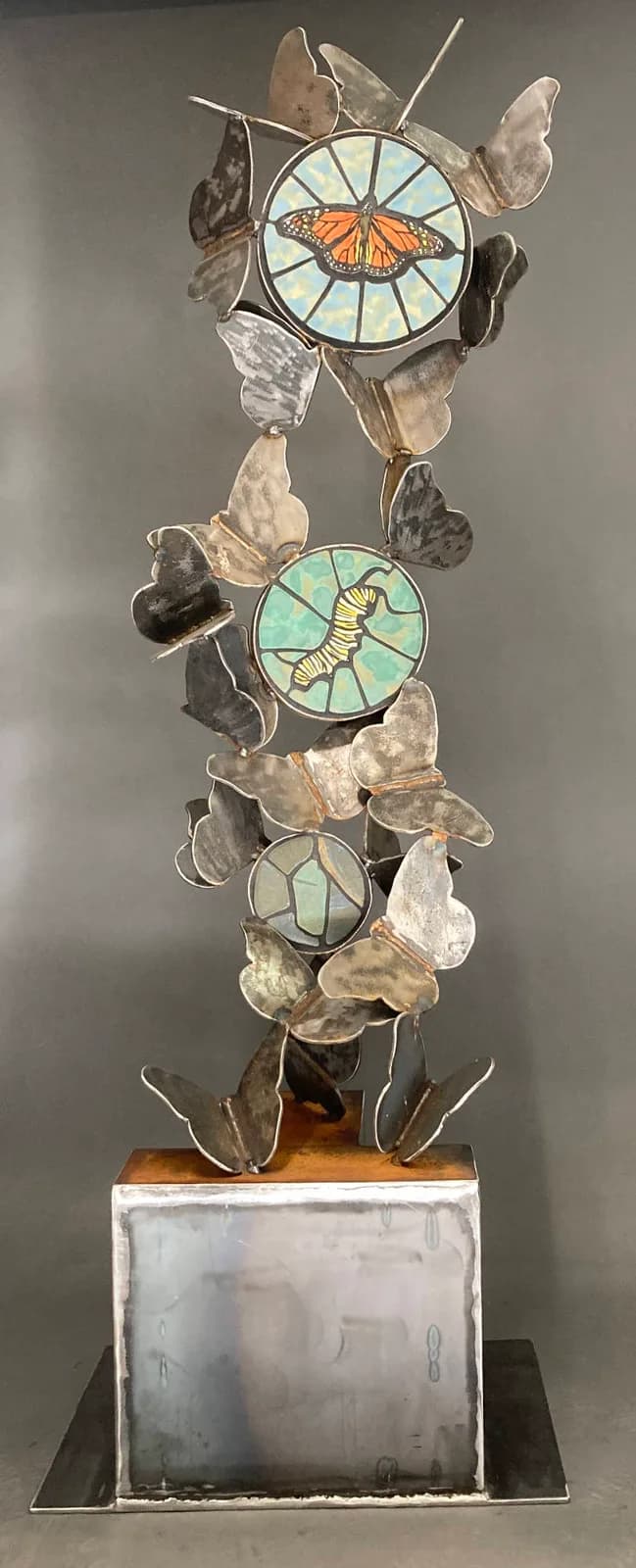 Stacked sculptural assemblage combining glass medallions with preserved butterfly and insect specimens.