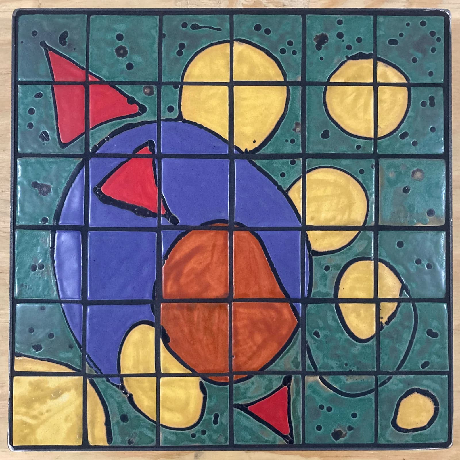 Abstract stained-glass panel with bold geometric shapes and primary colors in a gridded composition.