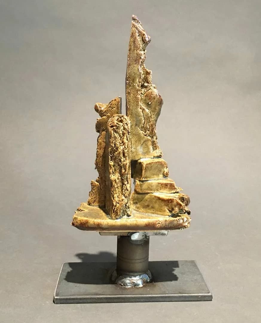 Abstract bronze sculpture with vertical stacked forms and organic surface texture mounted on a metal base.