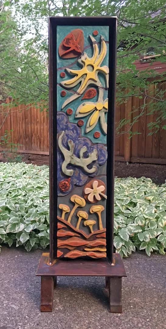 Painted wood relief panel featuring stacked botanical motifs: roses, starflowers, mushrooms, and vines in warm and cool tones.