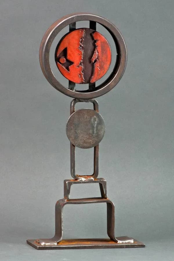 Abstract metal sculpture with red enameled rotating disc and geometric welded frame.