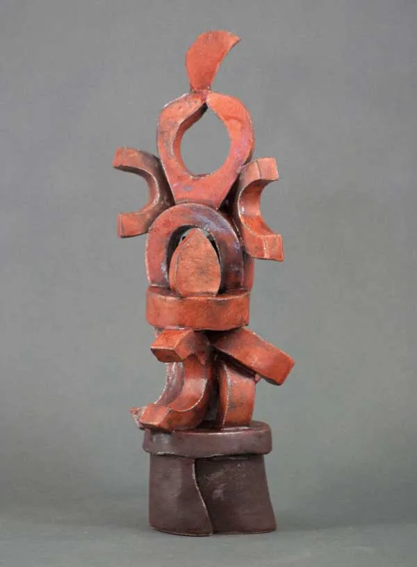 Abstract wooden sculpture with stacked curved and angular forms in warm coral and dark brown tones.