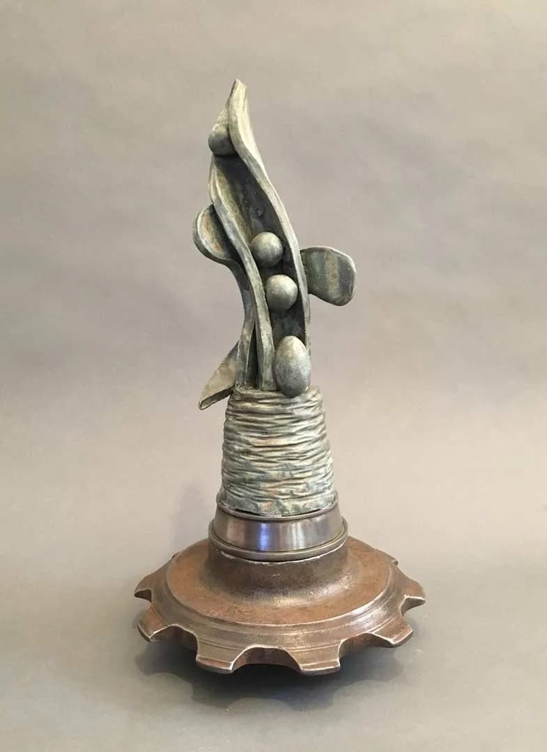 Cast metal sculpture with organic spiraling form, wrapped metal band, and decorative base.