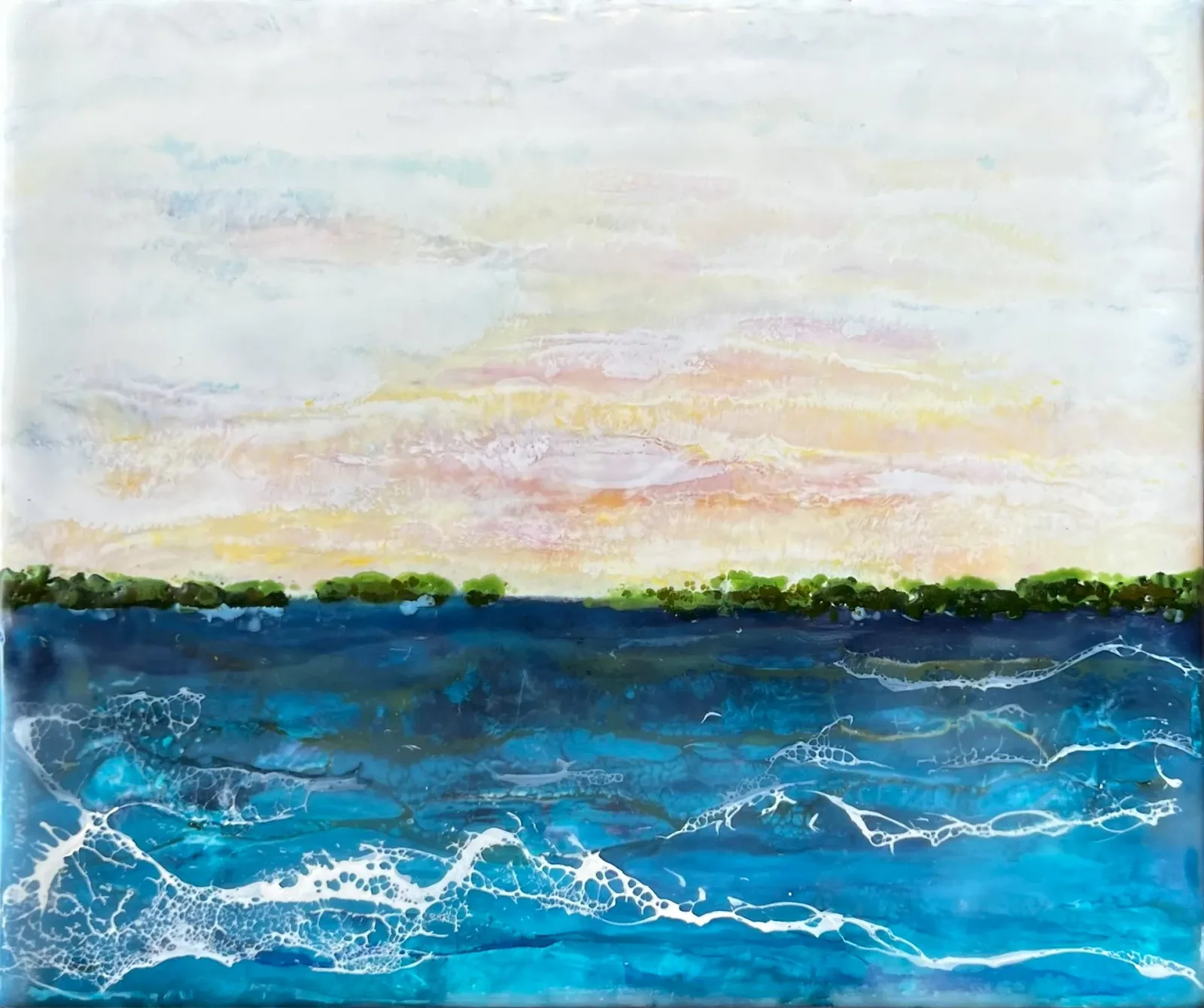 Seascape with dynamic waves and distant tree line beneath a soft, multicolored sky.