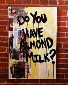 Street art mural with black text and collaged imagery on yellow background against brick wall.
