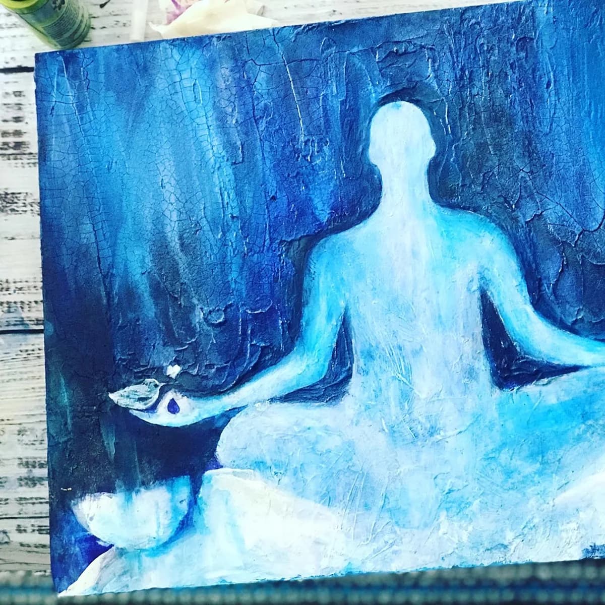 Seated meditation figure rendered in pale blue and white acrylic over deeply textured dark blue background.