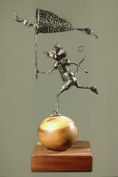 Abstract metal sculpture with wire and brass elements balanced on a wooden base.