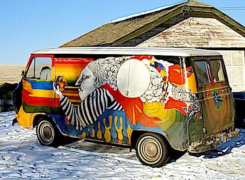 Colorful van mural with surreal portraits and geometric forms in thunderbird red, driftwood, and gunsmoke tones.