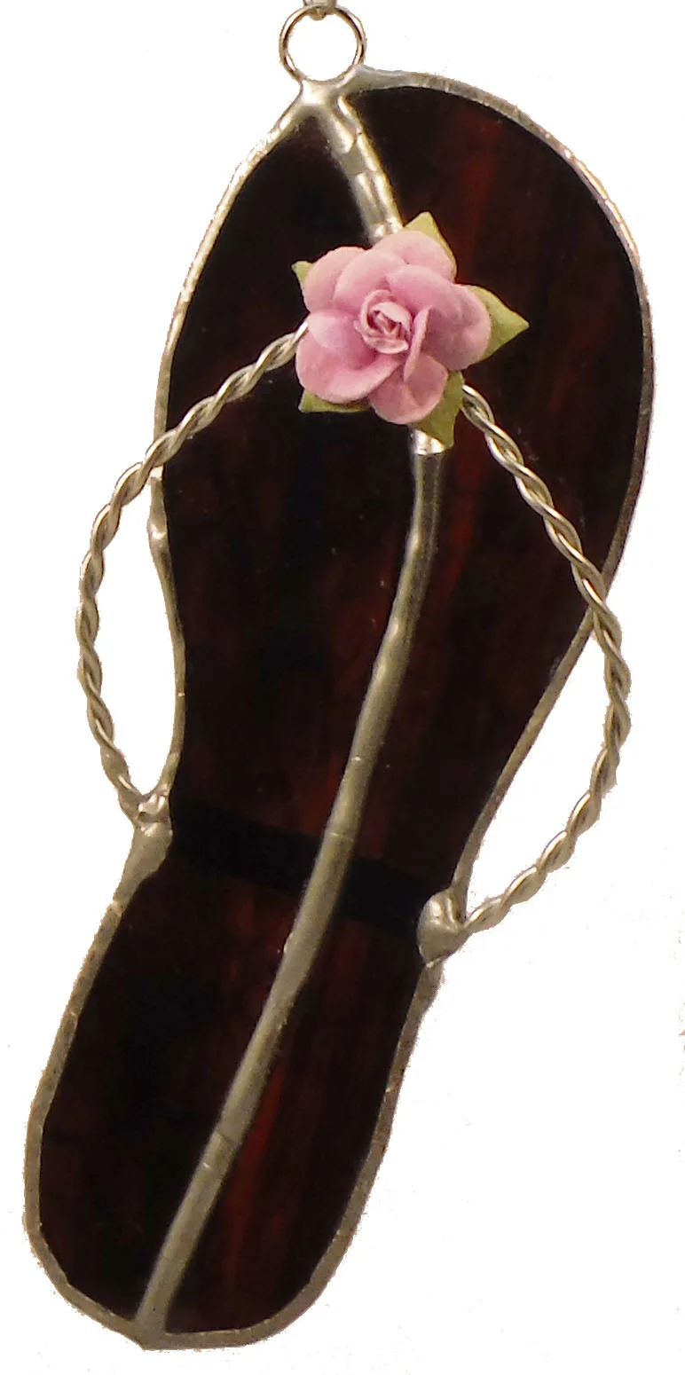 Pink rose enclosed in a dark tobacco-brown glass pendant with metal accents and twisted twine loop.