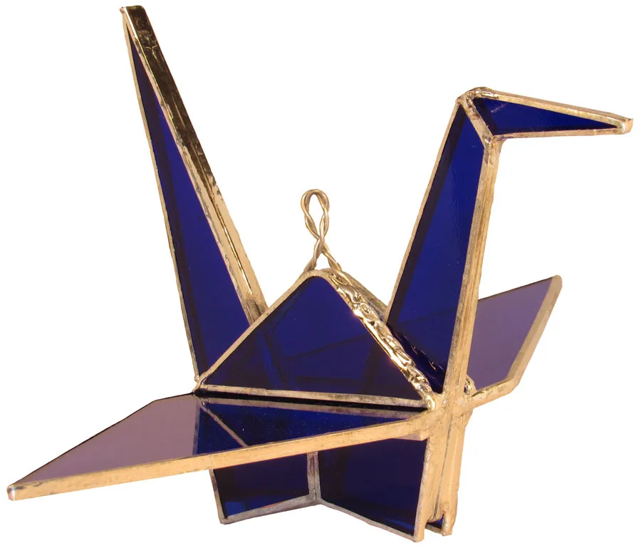 A geometric glass origami crane in deep sapphire and bleached cedar tones.