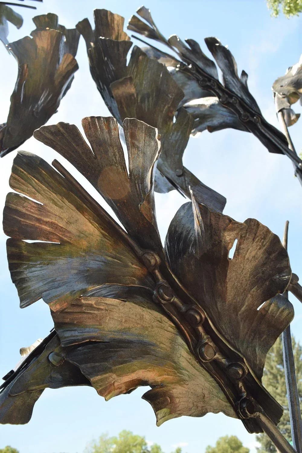 A bronze sculptural flower with layered petal forms rendered in rich shadow and golden-brown patina.