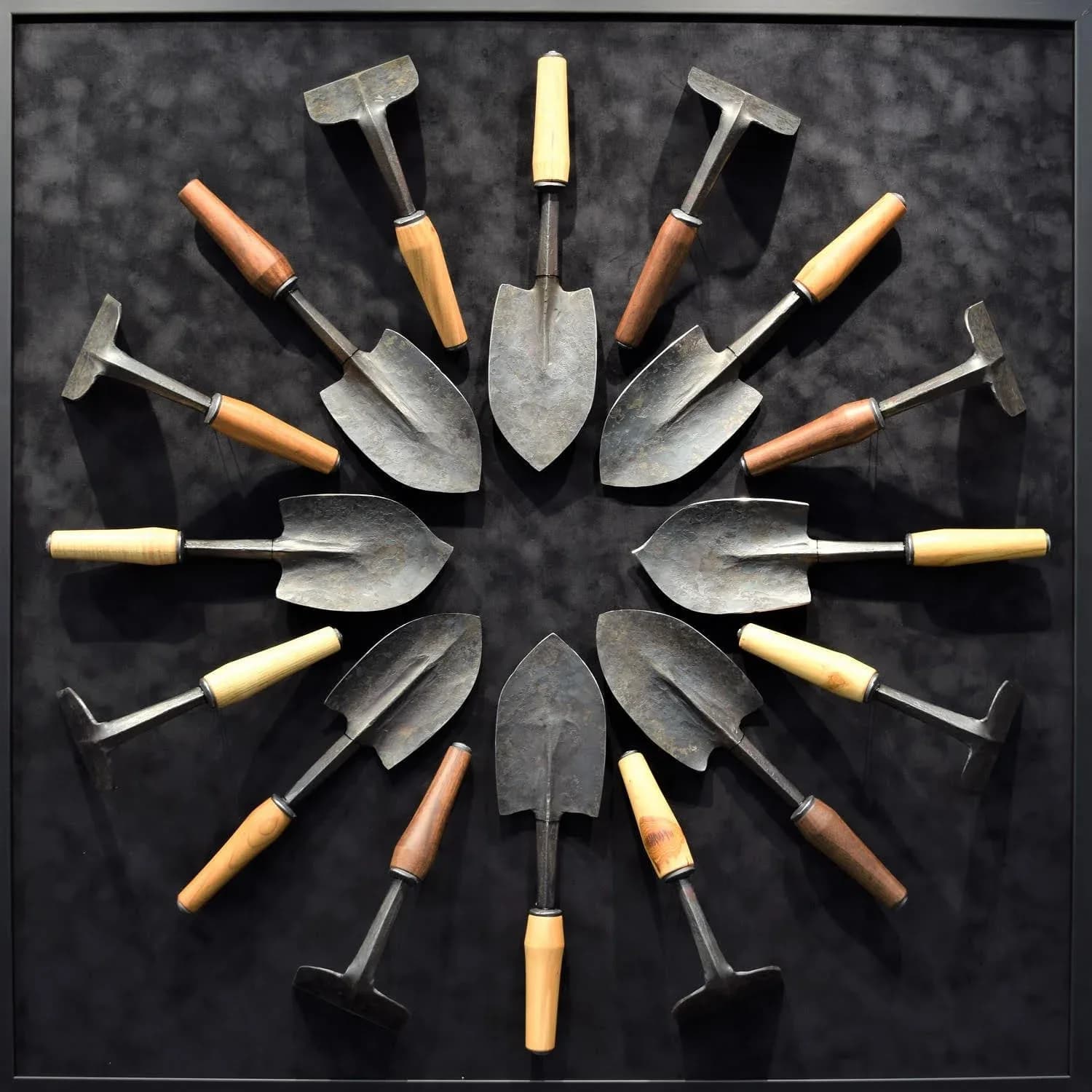 A symmetrical arrangement of vintage gardening hand tools radiates from a dark center in a mandala composition.
