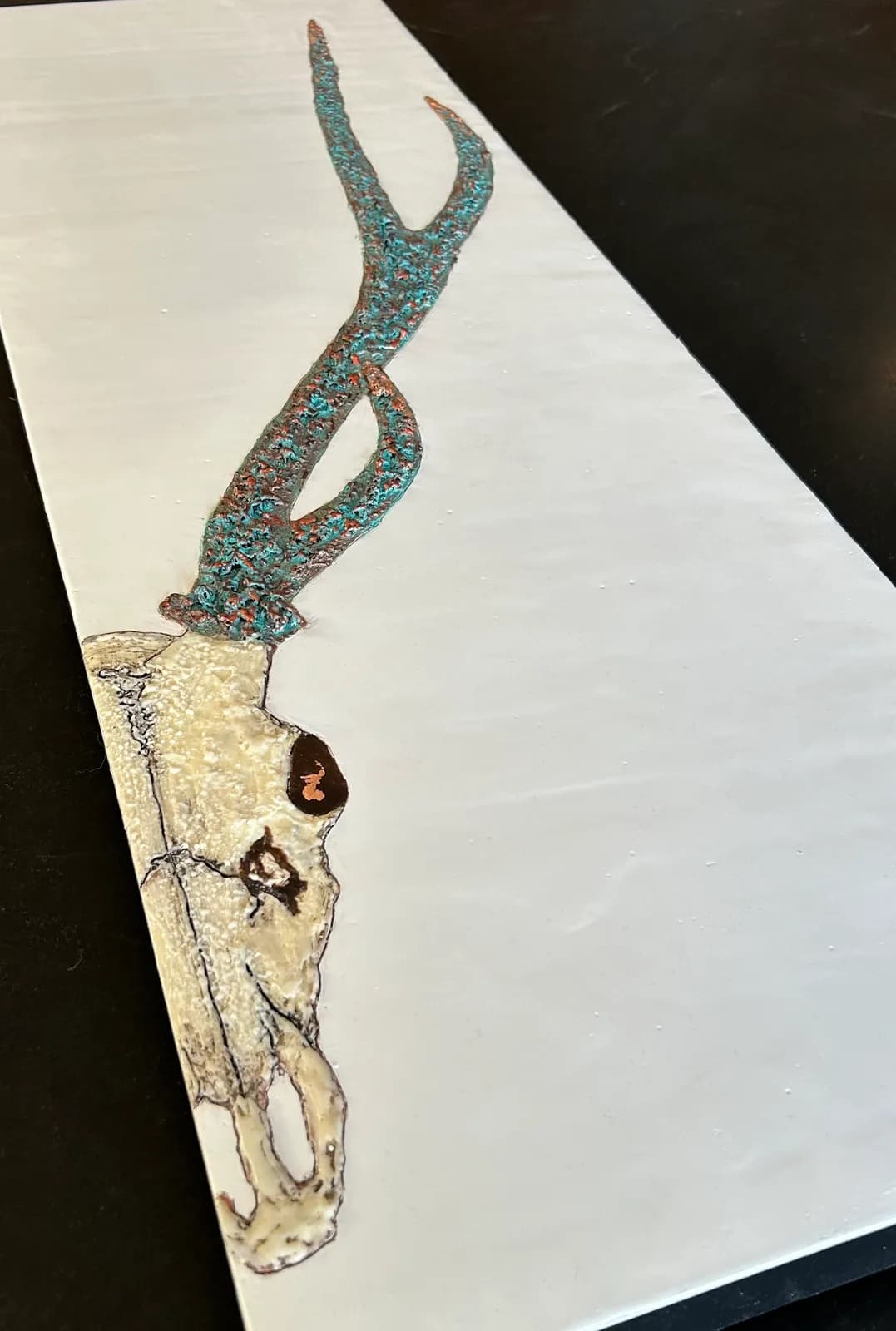 Antelope skull rendered in ink with turquoise patterning and coral reef-toned eye socket.