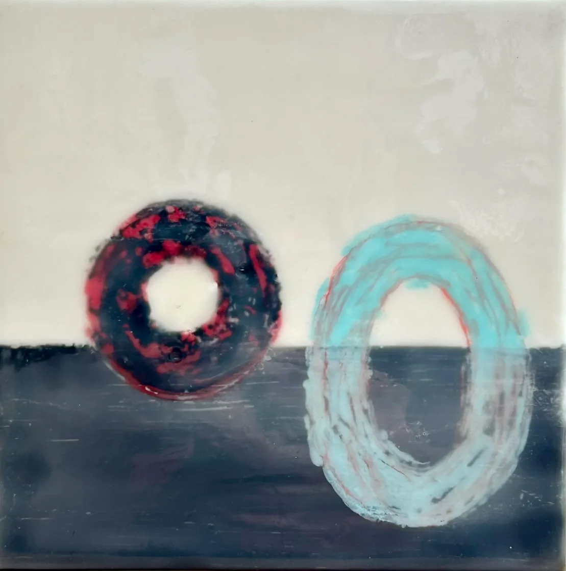 Two geometric rings—one wine berry and black, one celeste and cream—float above a dark Oxford blue horizon.