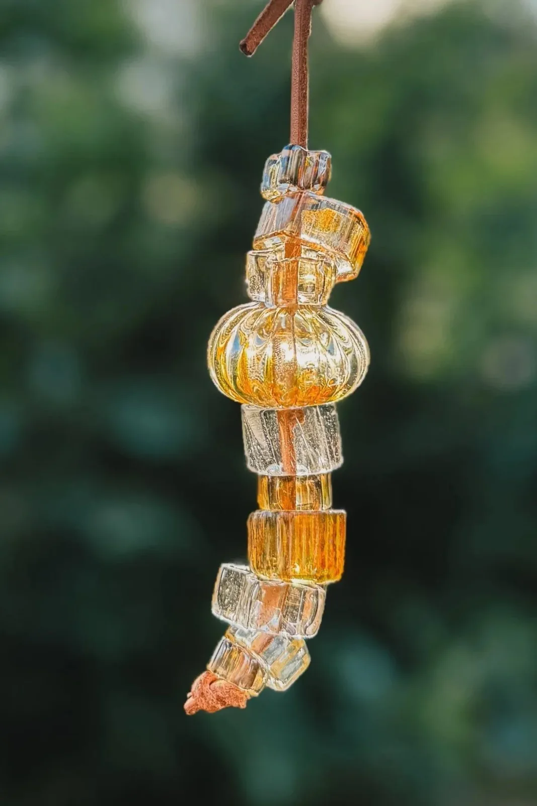 Stacked amber and clear glass beads suspended from copper leather cord.