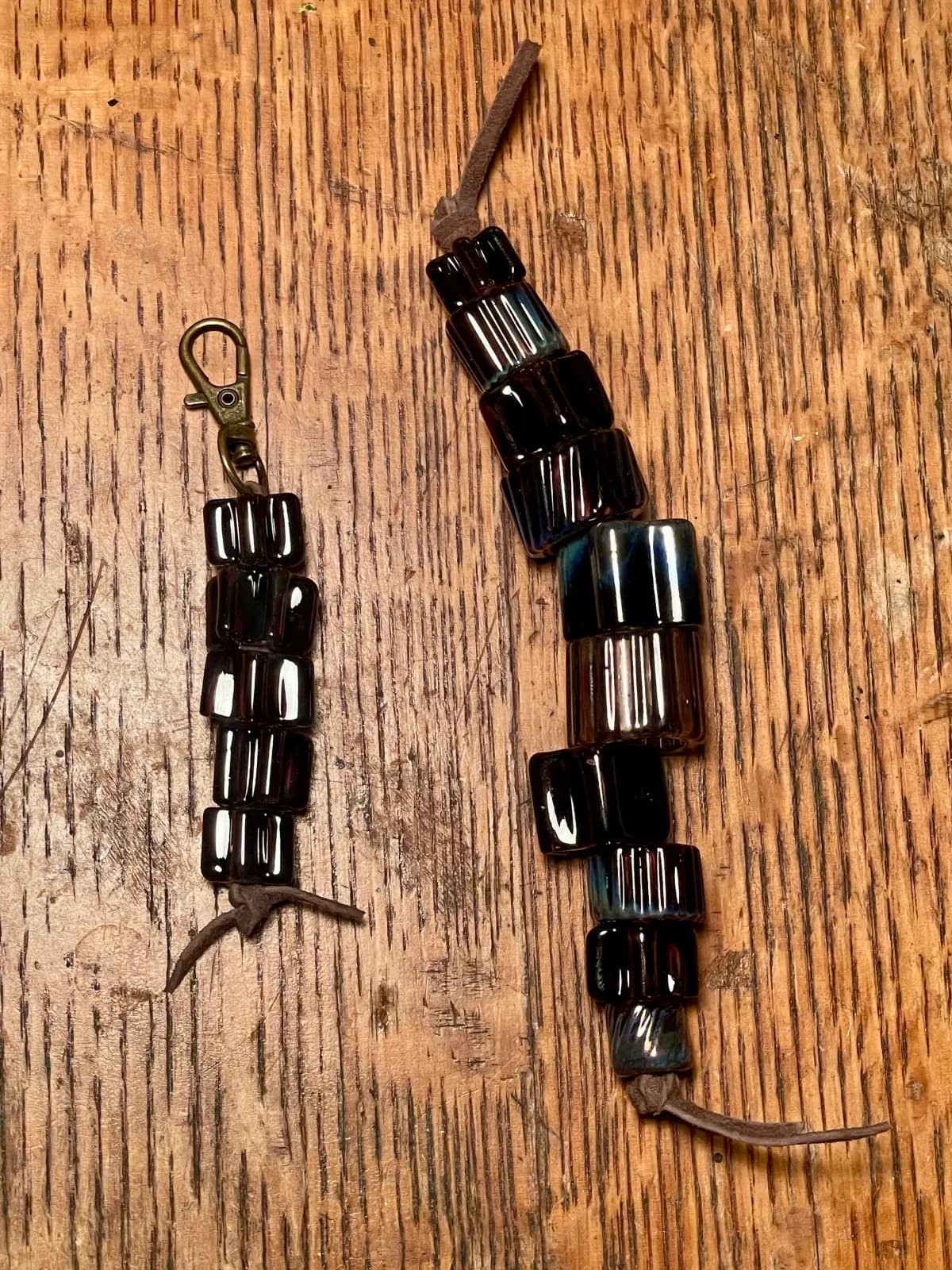 Two handcrafted metal kinetic sculptures with wood handles and antique brass hardware on wood.