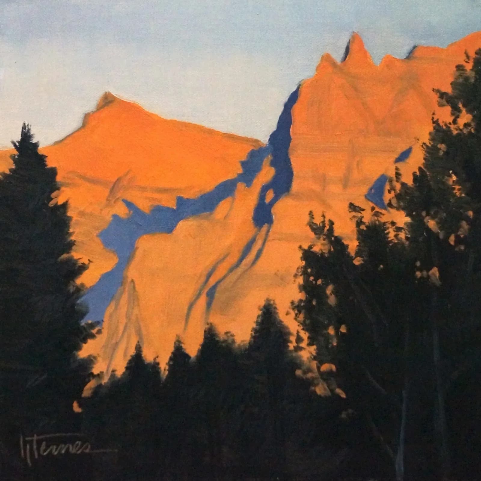 Boulder Flatirons bathed in jaffa-orange alpenglow at dawn, with dark conifer silhouettes below.