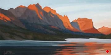 Sunrise light bathes the Boulder Flatirons in rust and red damask over a still alpine lake.