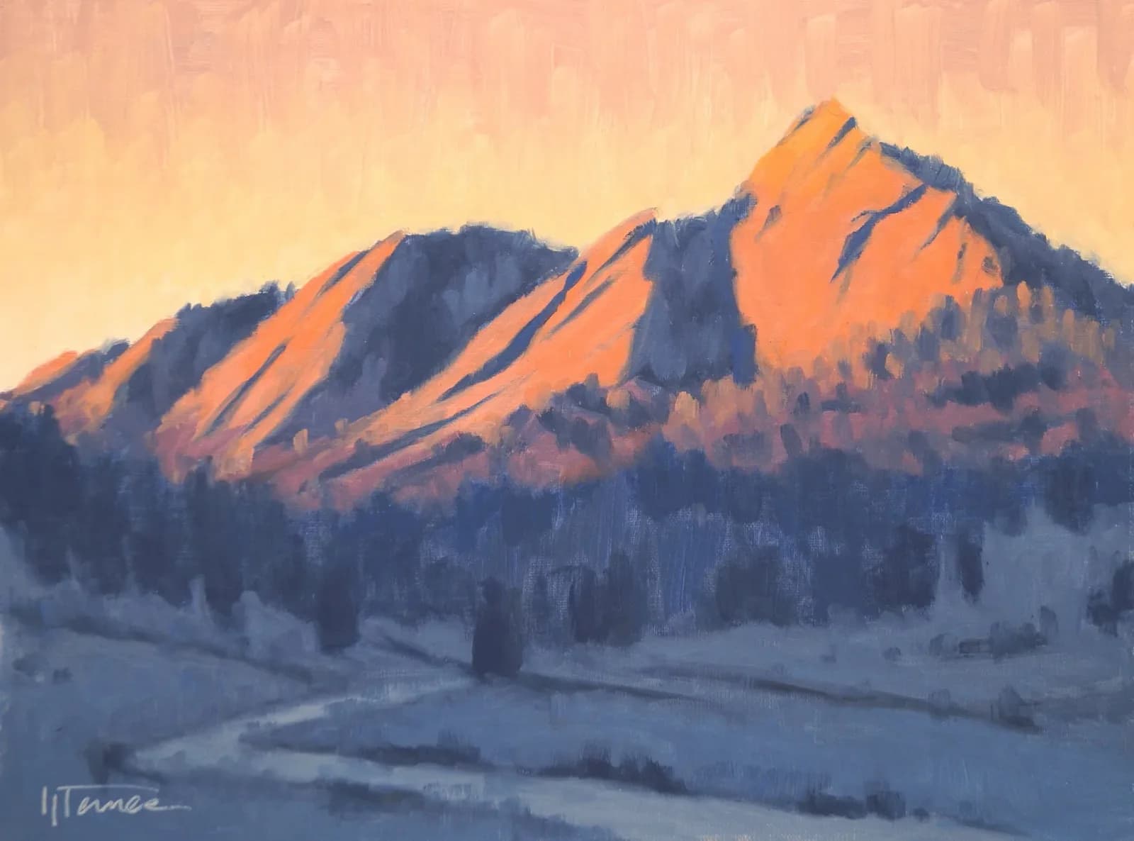 The Boulder Flatirons glow in warm alpenglow above a snow-covered valley at sunrise.