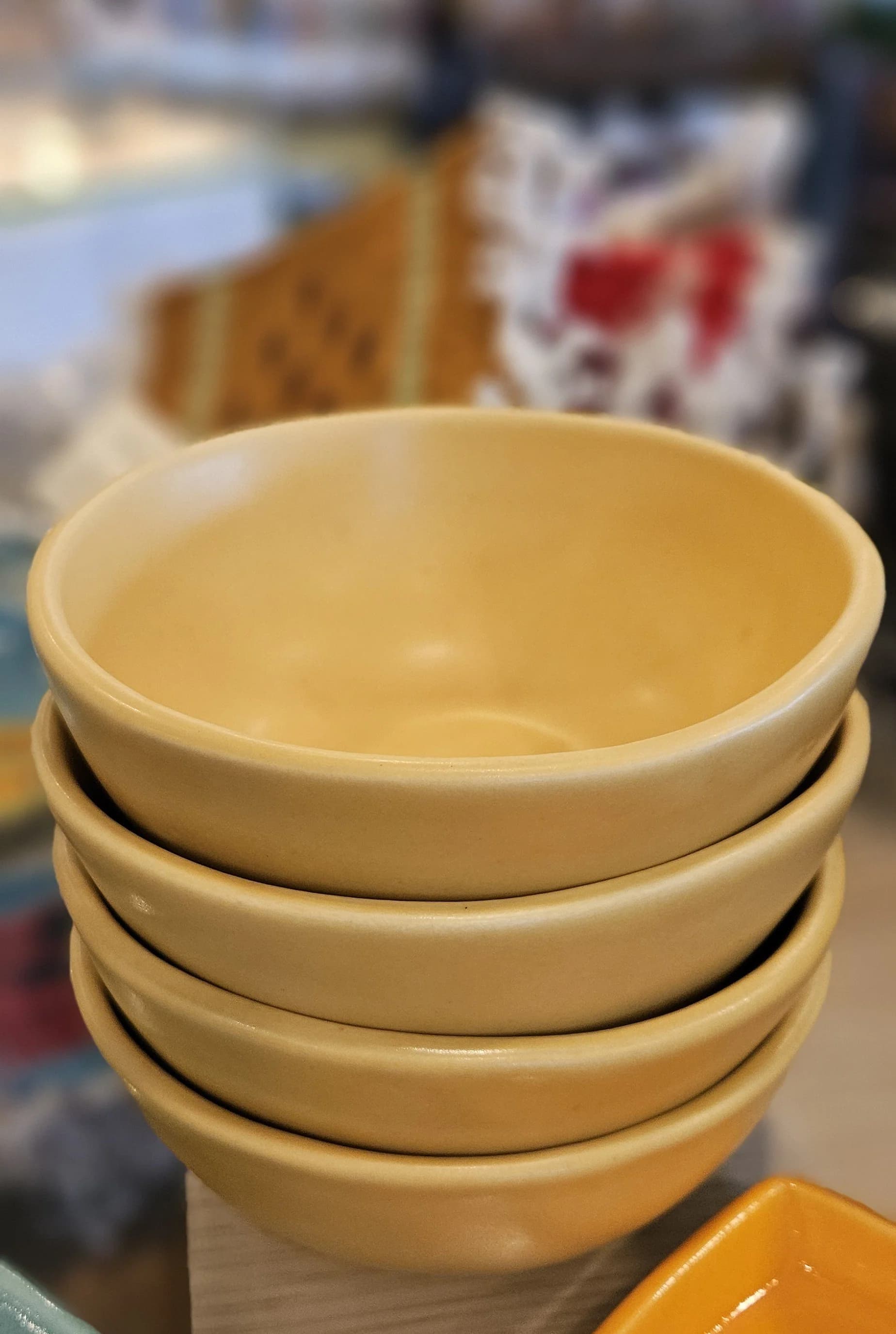 Stack of cream-colored ceramic bowls in a studio or workshop setting.
