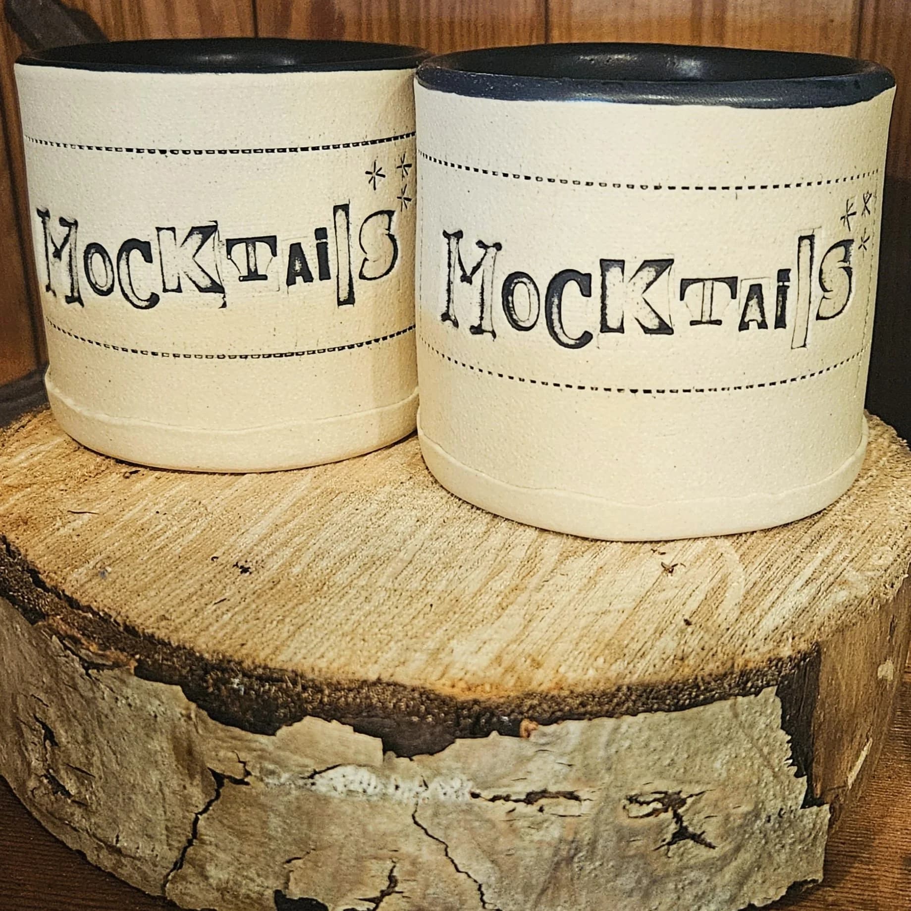 Two ceramic vessels labeled "Mocktails" displayed on a rustic wooden stump.